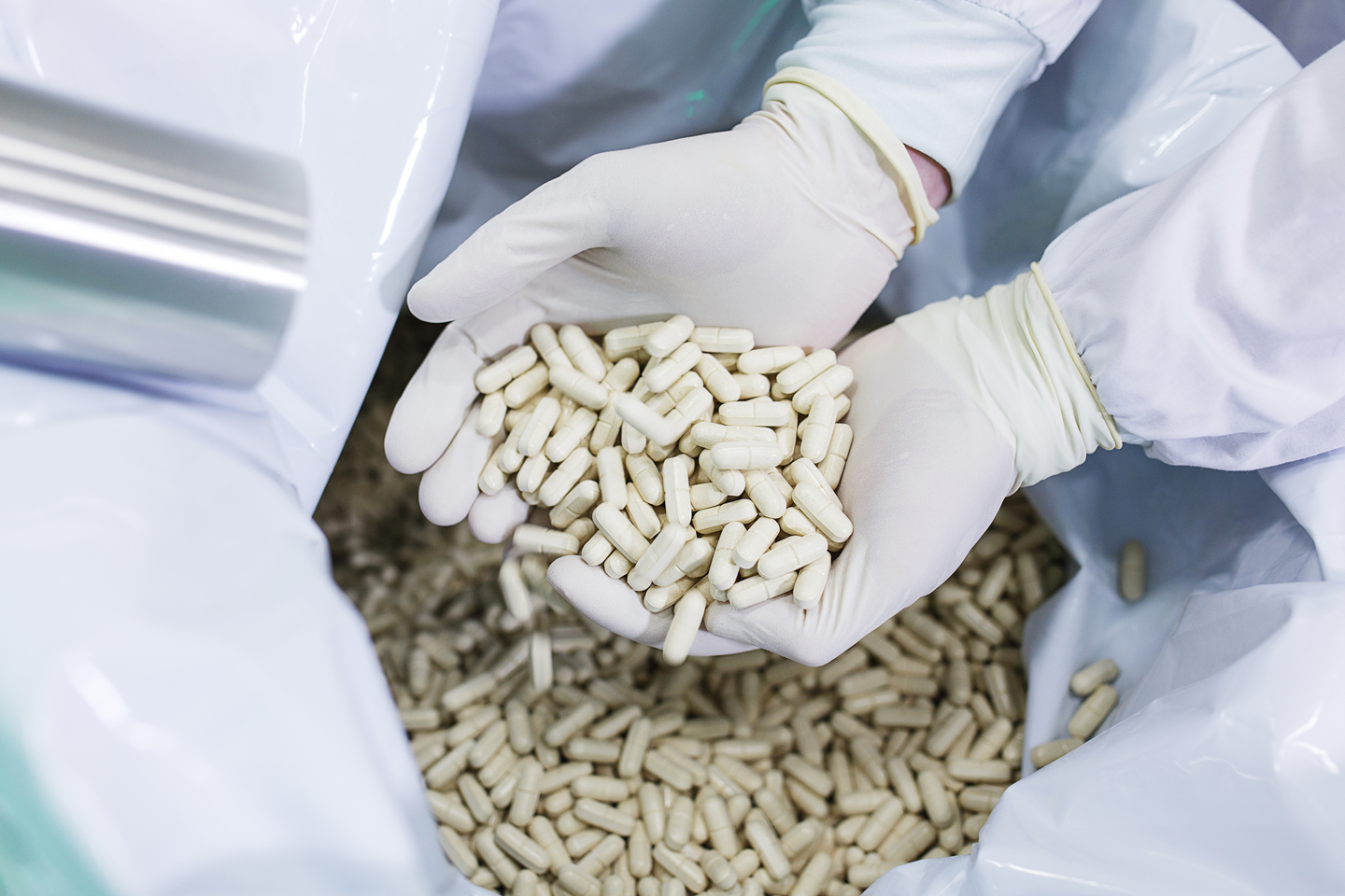 Pharmacist in the chemical production laboratory holds in two palms in sterile gloves manufactured tablets.